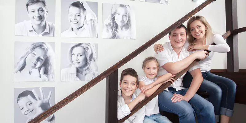 Loving family sitting on the stairs with their canvases displayed on the wall behind them