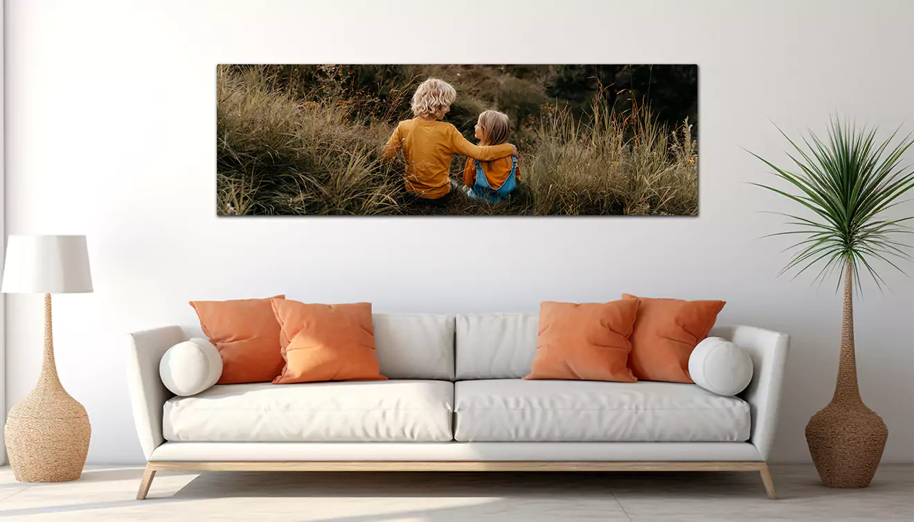 Panoramic canvas displayed in a lounge next to a couch, featuring two kids looking adoringly into each other's eyes - banner