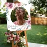"Square photo canvas on an easel featuring a floral design with pink and purple flowers, showcasing a smiling elderly person. The canvas has the text 'Celebrating Msizi' and is adorned with fresh flowers at the base. Ideal for personalised gifts, photo albums, and memory keepsakes."