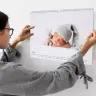 Woman hanging a personalised wall calendar featuring a sleeping baby in a grey knitted hat. The calendar is open to January 2023, showcasing a clean and minimalist design. Ideal as a photo gift, baby shower gift idea, or Christmas gift.