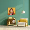 A modern living room with a green wall featuring a vibrant canvas print of a person with a colourful patterned headscarf. The room includes a wooden armchair with a yellow cushion, a matching wooden shelf with books and decorative items, and a white pendant lamp hanging from the ceiling.