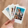 A hand holding a set of five printed photo cards, each featuring different outdoor scenes with people. The photos have a white border, resembling Polaroid-style prints. The background is blurred, highlighting the photo cards. Ideal for personalised gifts and photo albums.