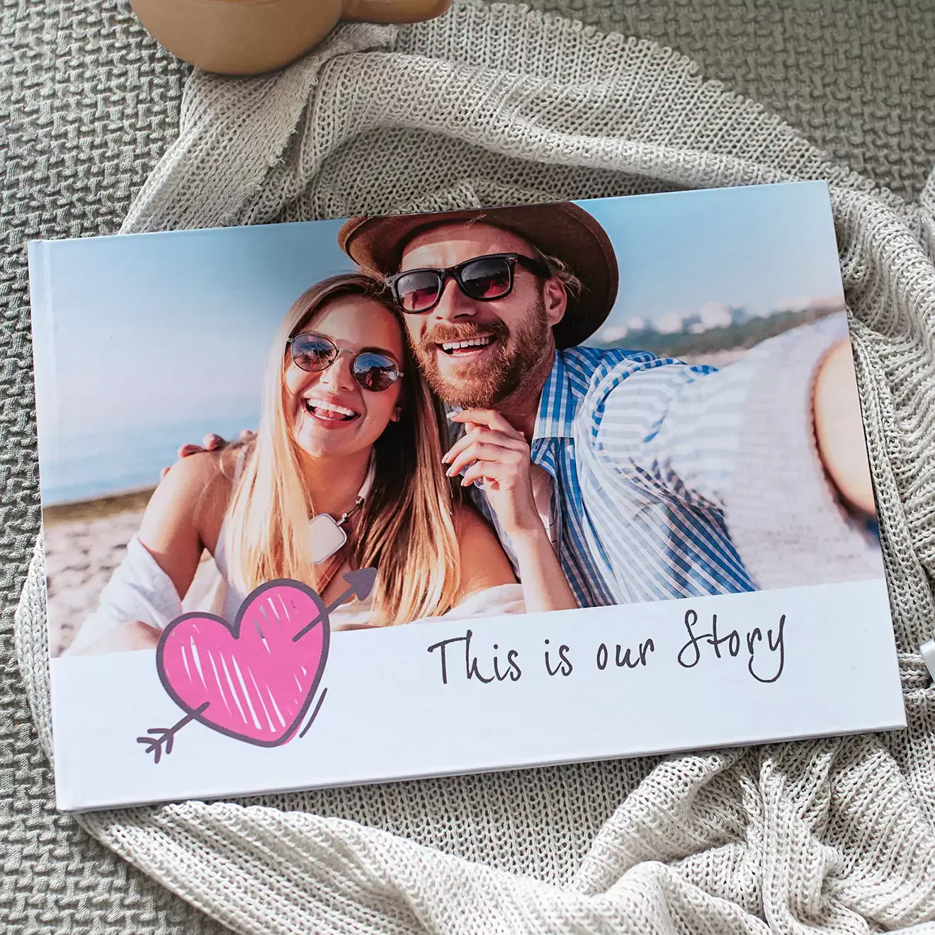 Personalised photo book with a cover featuring a smiling couple at the beach, adorned with a pink heart graphic and the text ''This is our Story.'' Ideal for gifts for men, baby shower gift ideas, Christmas gift ideas, and Valentine''s Day gift ideas. Perfect for creating a photo album book or photo books albums.