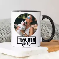 White ceramic mug with the phrase "Teacher Fuel" in black lettering, featuring a small coffee cup illustration with a heart. The mug is being held by a person in a blue shirt. Ideal as a personalised gift for teachers, suitable for various occasions such as Christmas or birthdays.