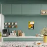 A modern kitchen with teal cabinets and a terrazzo countertop, featuring a personalised photo canvas on the wall. The canvas displays a person wearing a hat and holding a sunflower. The kitchen also includes a coffee machine, mugs, wooden utensils, and decorative plants. Ideal for personalised gifts in South Africa.