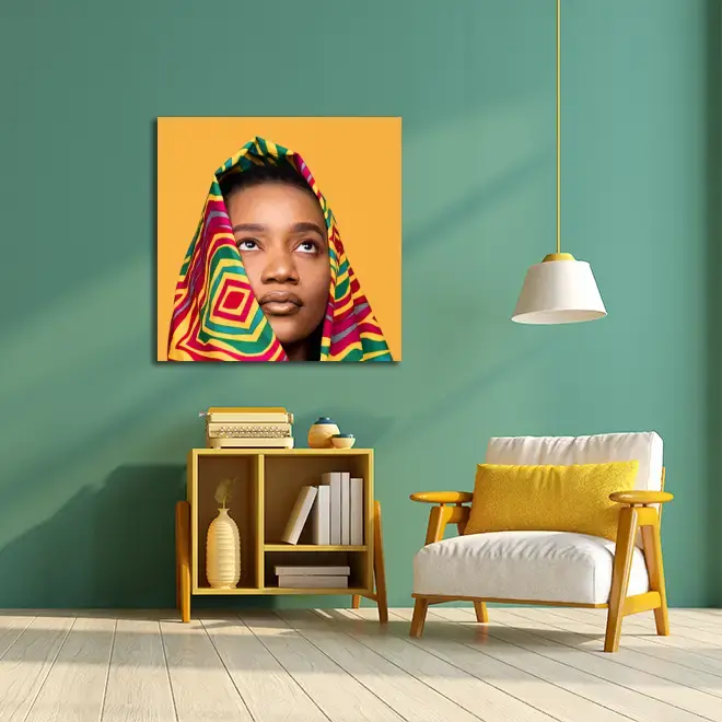 A vibrant living room features a colourful canvas print of a person with a patterned headscarf against a yellow background. The room has a green wall, a wooden bookshelf with books and decor, a white and yellow cushioned chair, and a hanging white lamp. Ideal for personalised gifts in South Africa.