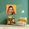 A vibrant living room features a colourful canvas print of a person with a patterned headscarf against a yellow background. The room has a green wall, a wooden bookshelf with books and decor, a white and yellow cushioned chair, and a hanging white lamp. Ideal for personalised gifts in South Africa.