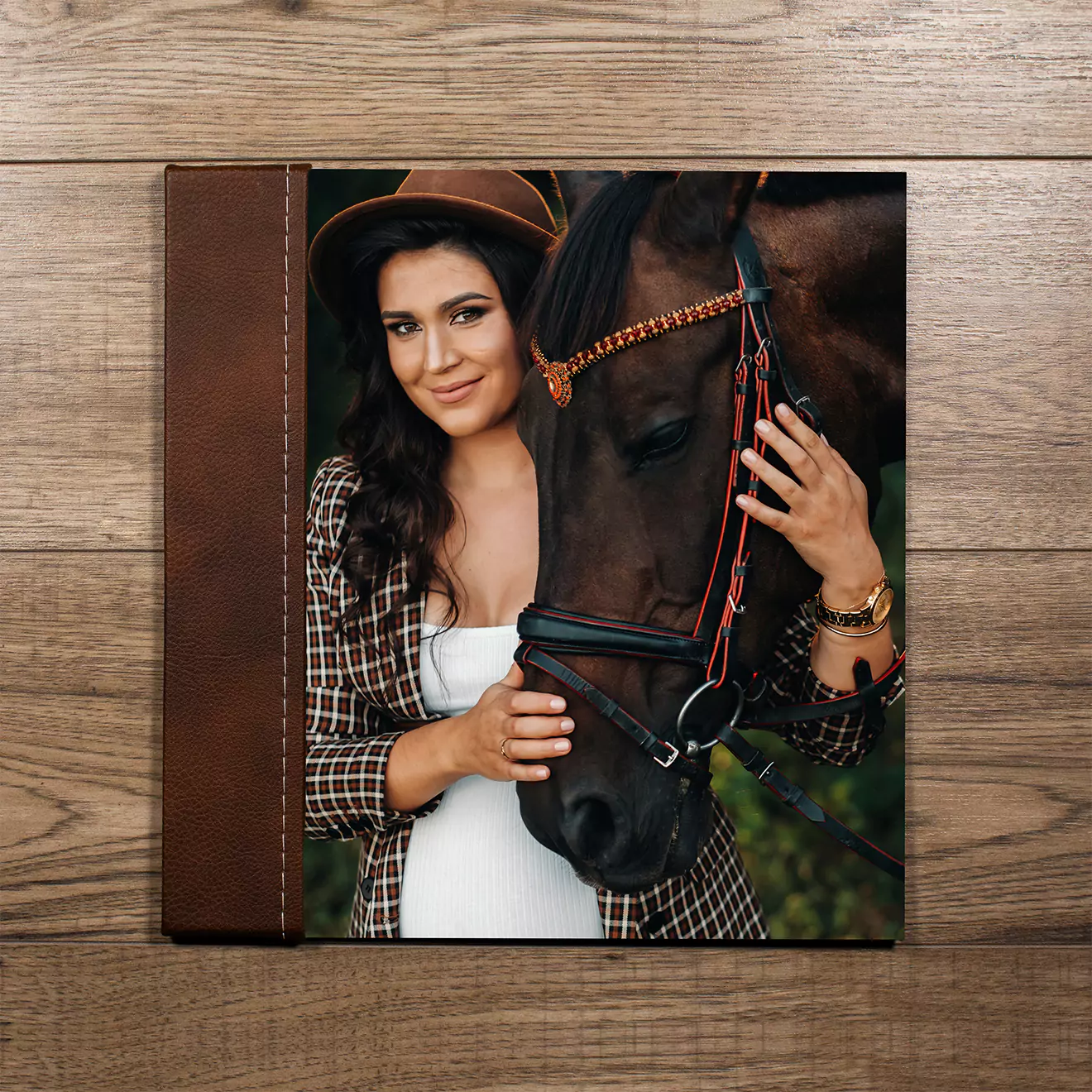 Photobook cover featuring a woman in a hat and plaid shirt, affectionately holding a horse. The cover has a brown leather spine and is set against a wooden background.