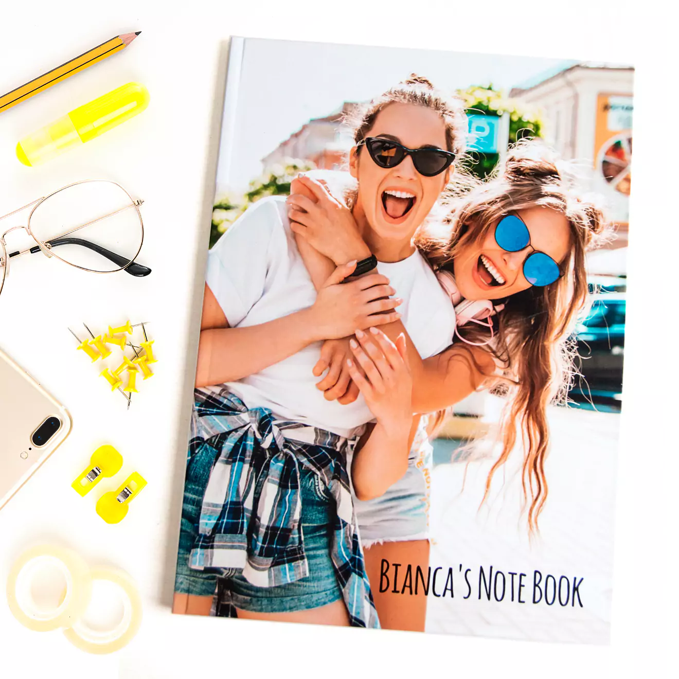 Personalised notebook with a custom cover featuring two women smiling and hugging, titled 'Bianca's Note Book'. Surrounded by stationery items including a pencil, glasses, and sticky notes. Ideal for gifts for her, Christmas gifts, or personalised gifts in South Africa.