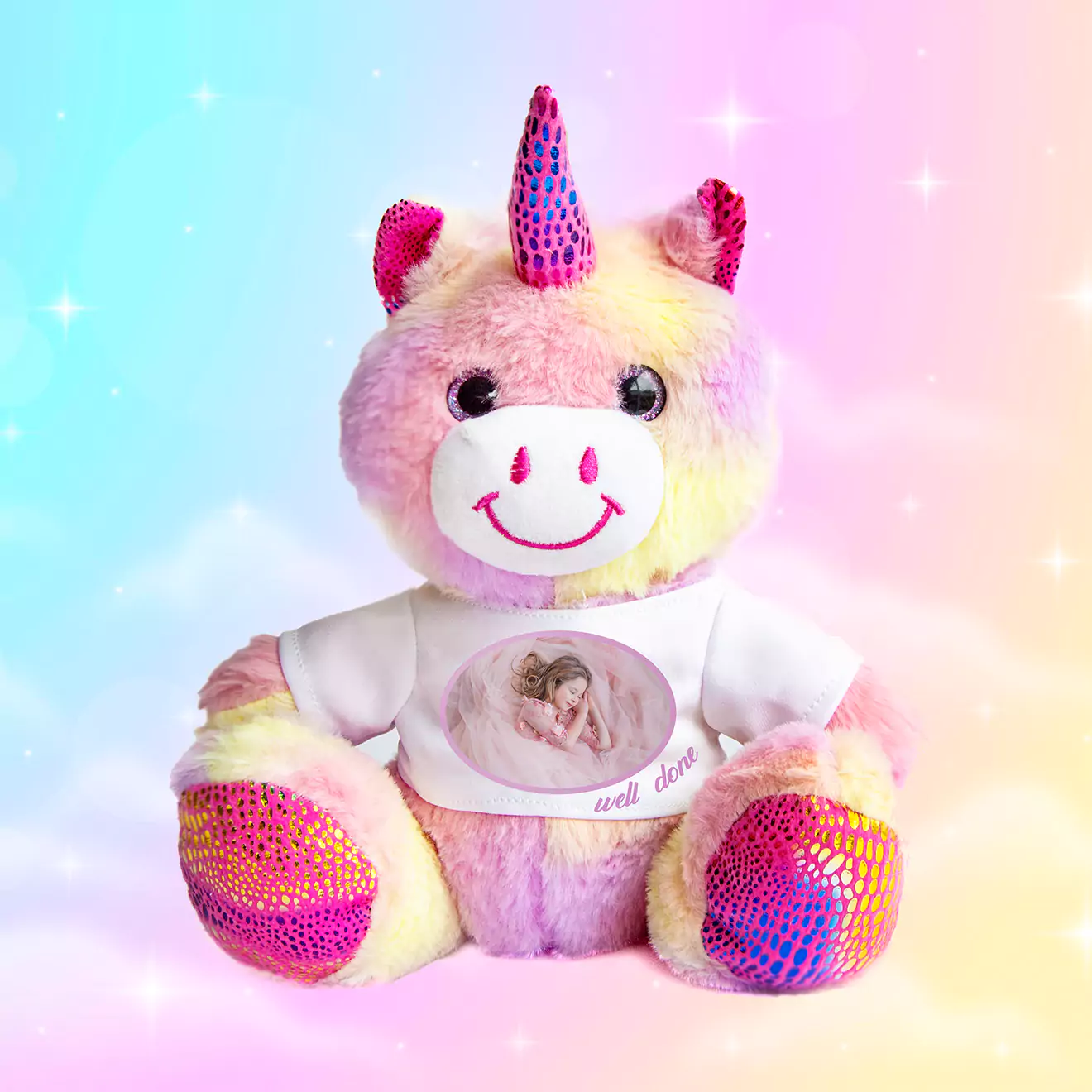 A colourful plush unicorn toy with a personalised photo and text on its white t-shirt, set against a pastel rainbow background. Ideal for baby gifts and personalised presents.