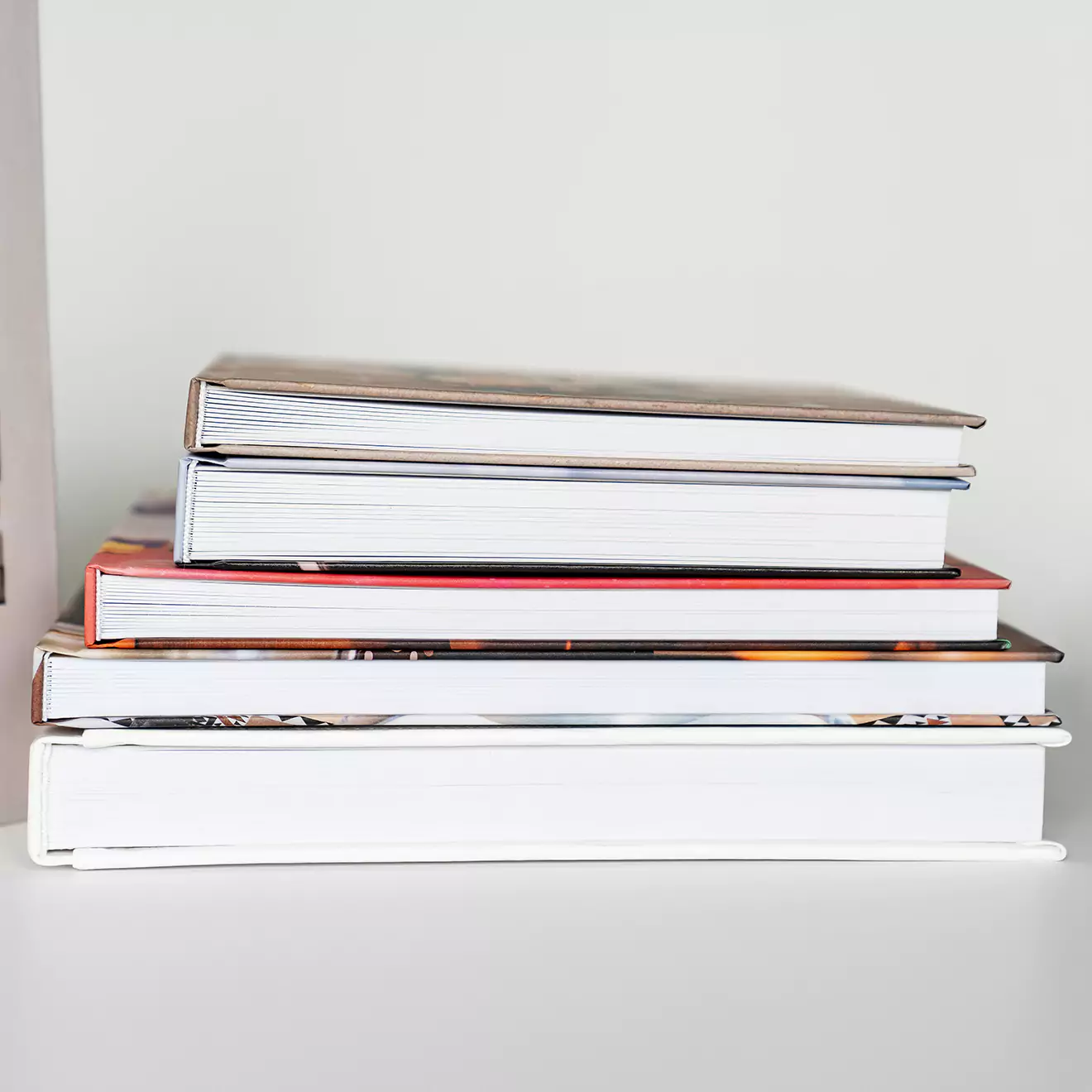 A colourful pile of photobooks stacked together, representing the great savings you get when photobooks are on special at RapidStudio. Create more for less with our exclusive discounts.