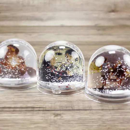 Collection of three personalised snow globes displayed together, each with unique images inside including a winter-clad individual, enhancing any space with their magical, snowy charm.