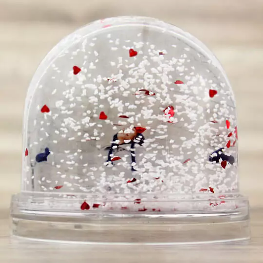 Personalised snow globe filled with floating hearts instead of traditional snow, encasing a romantic scene that celebrates love and affection, perfect as a gift or decorative keepsake.