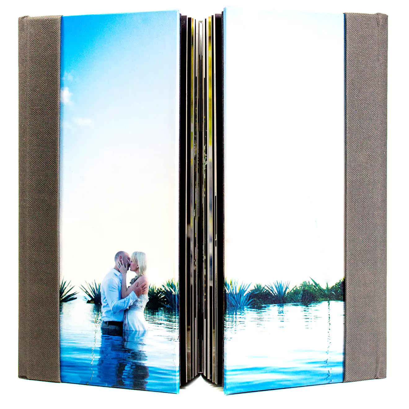 Open photobook with a glossy cover featuring a couple embracing in a serene water setting. The photobook has a high-quality finish and is designed for preserving cherished memories.