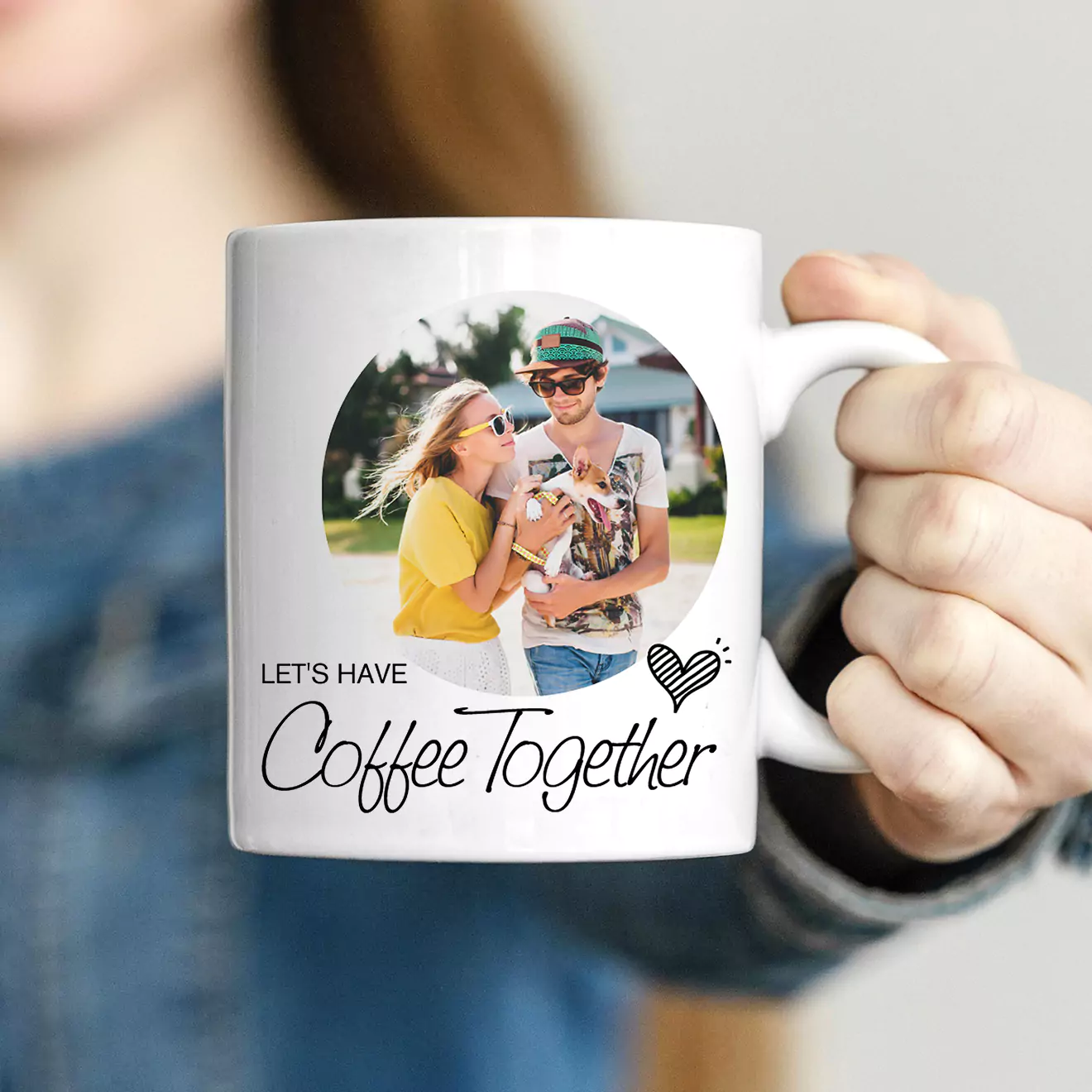 A person holding a white mug featuring a photo of a couple enjoying a drink together. The mug has the text "LET'S HAVE Coffee Together" with a small heart graphic.