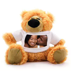 A soft, brown teddy bear wearing a white T-shirt featuring a personalised photo of a smiling couple. The teddy bear has a friendly expression with a black nose and light brown paws. Ideal for personalised gifts in South Africa, perfect for occasions like Valentine's Day, baby showers, or birthdays.