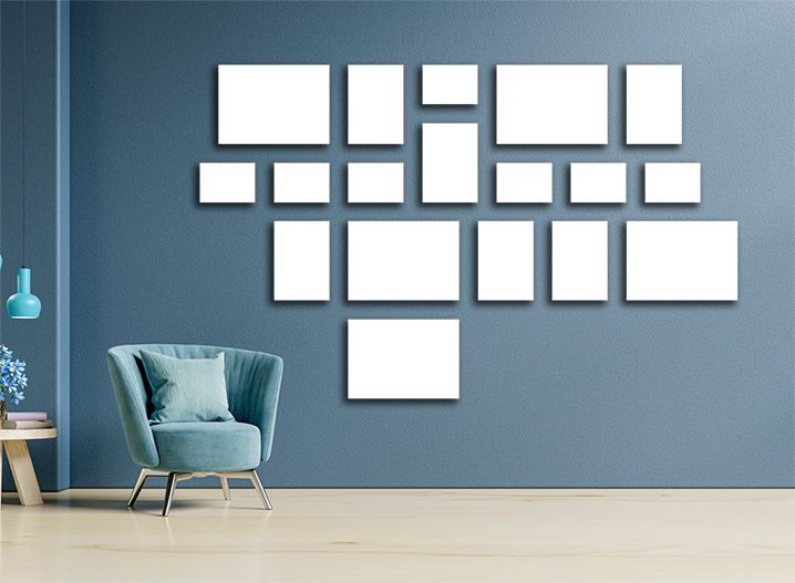 18-piece canvas set displayed on a blue wall, featuring various sizes and shapes in shades of black, red, and grey. The arrangement creates a modern and stylish look, perfect for home décor. A light blue armchair with a cushion is placed to the left, adding a cosy touch to the setting.