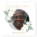 Funeral-themed floral collage photobook cover featuring a circular photo of an elderly woman with glasses, surrounded by white flowers and green leaves. The text 'Celebrating a life of' is written in elegant script above the photo, with the name 'Mandisa Zondi' below.