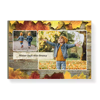 Hardcover photobook with an autumn theme, featuring a cover design with vibrant fall leaves and wooden background. The cover displays two photos of a child enjoying autumn, with the text 'Winter Days with Granny.' Ideal for personalised gifts, photo albums, and special occasions.