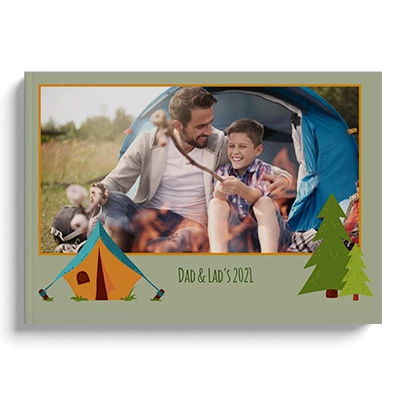 Hardcover camping-themed photo book featuring a cover image of a father and son sitting in front of a tent, with the text "Dad & Lad's 2021." The cover is decorated with illustrations of a tent and a tree, making it an ideal personalised gift for camping enthusiasts. Suitable for various occasions such as Christmas, Father's Day, or birthdays.