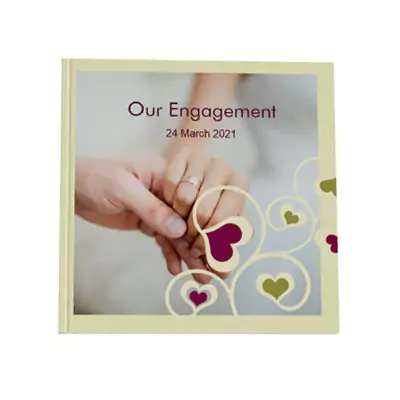 Hardcover photobook with a 'Love Tree' theme, featuring a cover image of two hands with engagement rings and the text 'Our Engagement' and '24 March 2021'. The design includes heart motifs in pink and green. Ideal for personalised gifts, engagement memories, and photo albums.