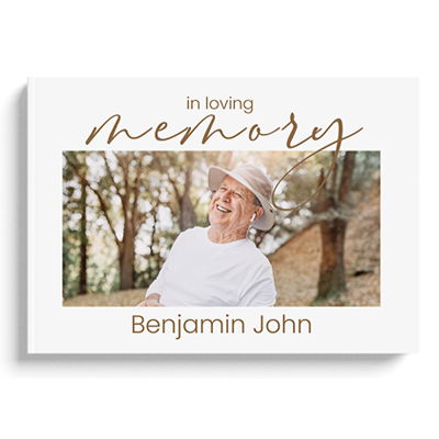 Hardcover memory book with a white cover featuring a photo of an elderly man smiling outdoors. The text 'in loving memory' is written in elegant gold script above the photo, with the name 'Benjamin John' below. Ideal for personalised gifts, photo albums, and memorial keepsakes.