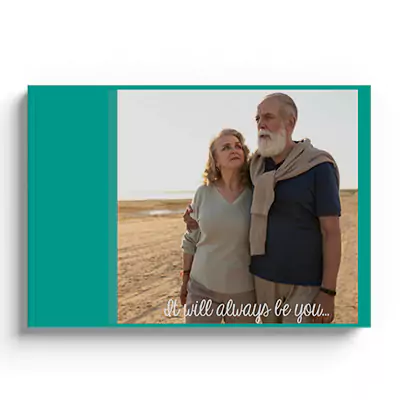 Hardcover photobook with a 'Natural Love' theme, featuring a teal cover and a photo of an elderly couple embracing on a beach. The text 'it will always be you...' is printed on the cover. Ideal for personalised gifts, photo albums, and special occasions like Valentine's Day or anniversaries.