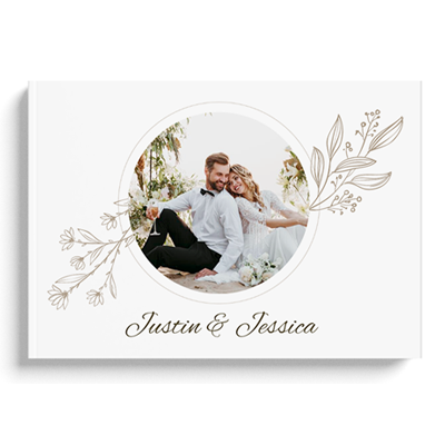 Elegant hardcover wedding photo album featuring a couple's image in a circular frame on the front cover. The design includes delicate floral illustrations and personalised names "Justin & Jessica" in stylish script. Ideal for preserving wedding memories and makes a thoughtful gift idea.