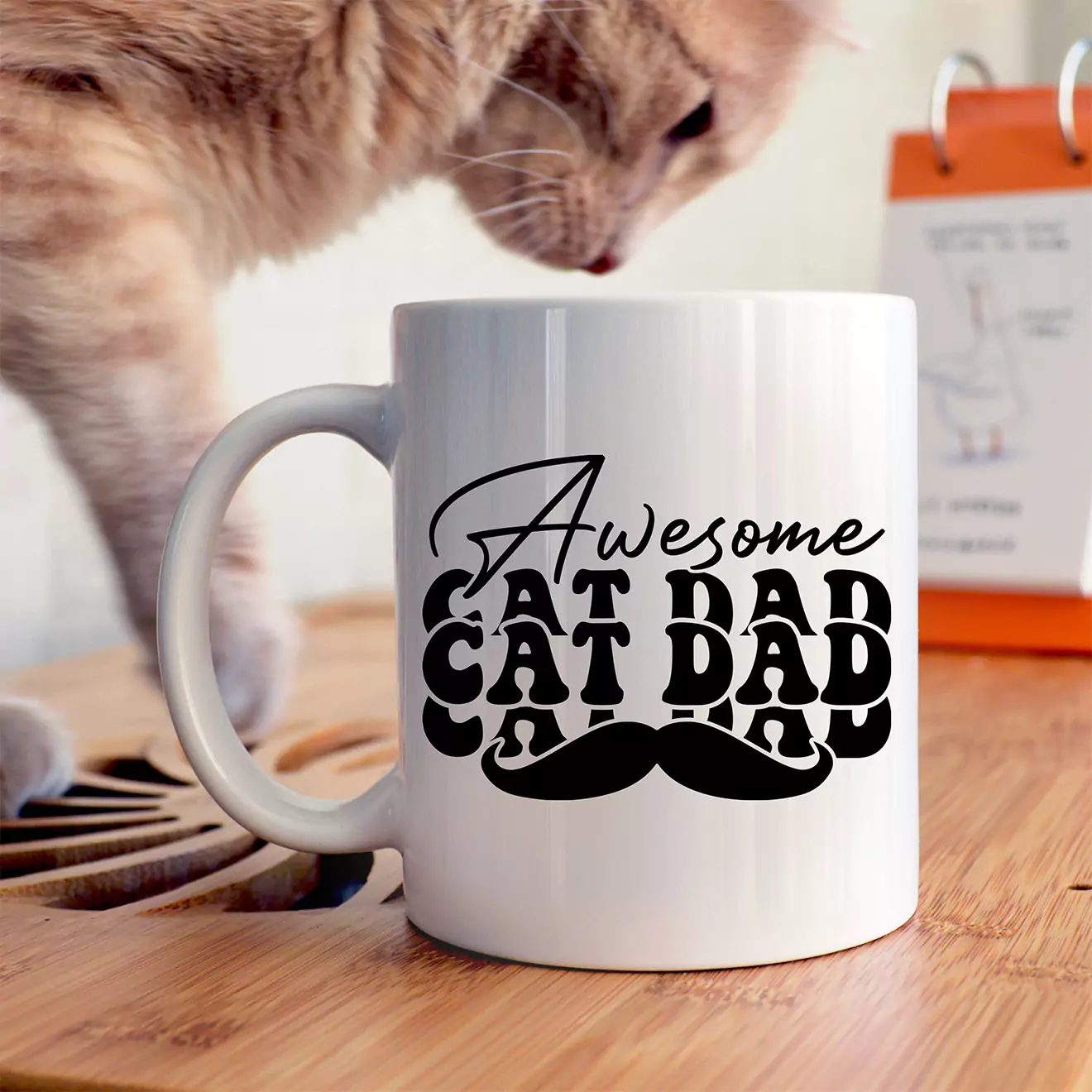 White ceramic mug with black text that reads "Awesome Cat Dad" and features a moustache graphic. The mug is placed on a wooden surface with a cat in the background. Ideal for gifts for men, especially cat lovers, and suitable for occasions like Father's Day or birthdays.