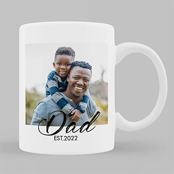 White ceramic mug featuring a heartwarming photo of a father and child, with the text "Dad EST. 2022" in elegant black script below the image. Ideal for personalised gifts, especially for new dads. Perfect for occasions like Father's Day, birthdays, or Christmas.