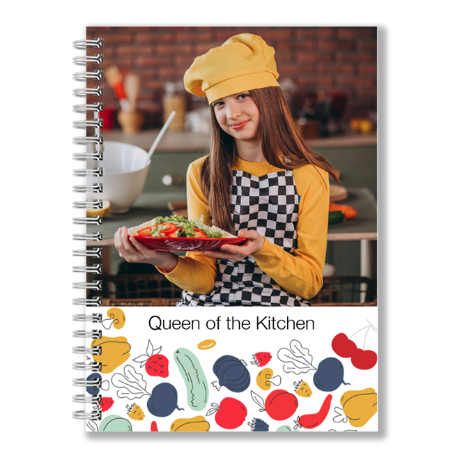 Spiral-bound recipe notebook featuring a cover image of a young girl in a chef's hat and apron, holding a plate of food. The bottom section of the cover has colourful illustrations of vegetables and the text "Queen of the Kitchen." Ideal for personalised gifts and cooking enthusiasts.