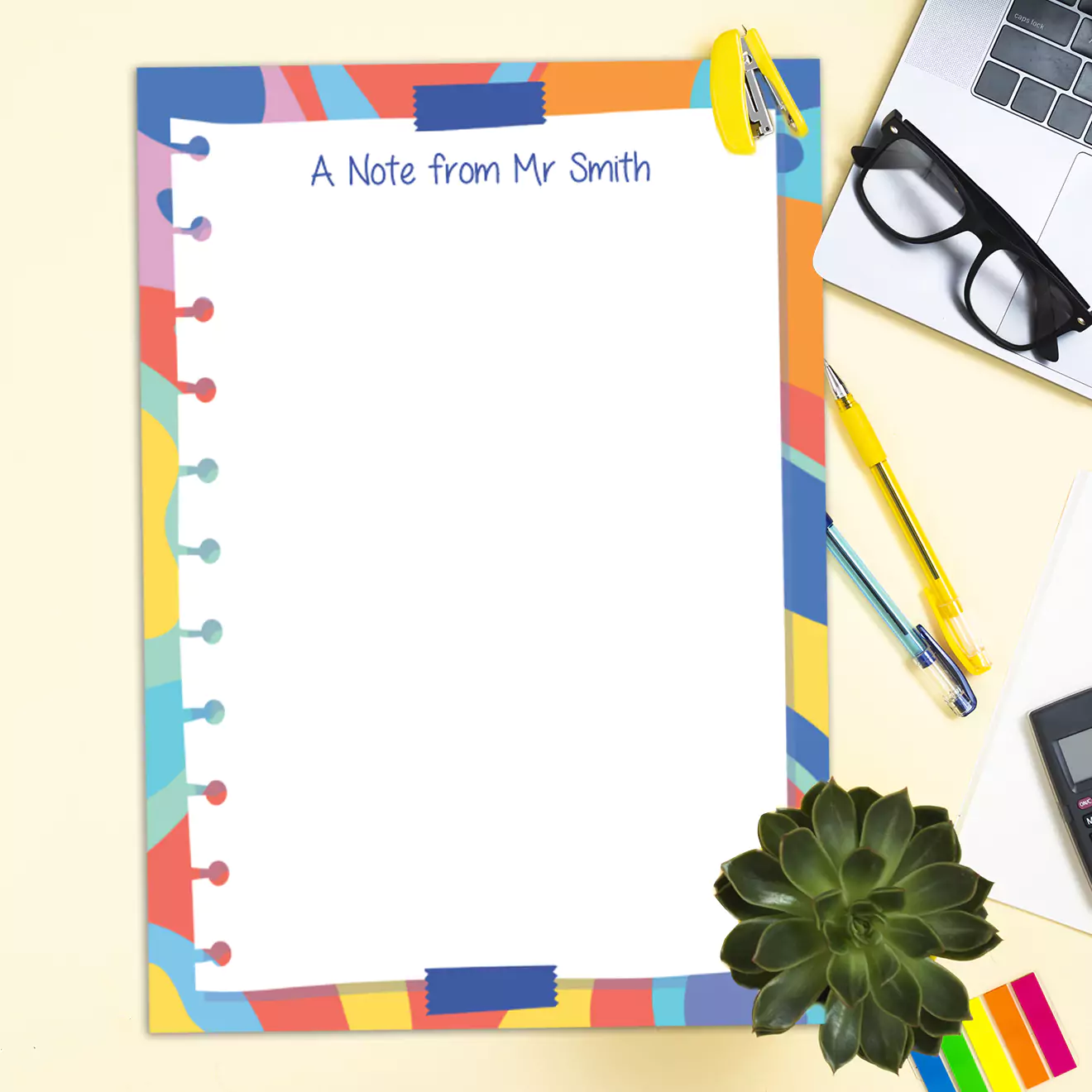 Colourful notepad titled "A Note from Mr Smith" with a vibrant, multicoloured border and a playful design. The notepad is placed on a desk alongside a pair of glasses, pens, a laptop, a succulent plant, and a notebook. Ideal for personalised gifts, teacher gifts, or fun stationery.