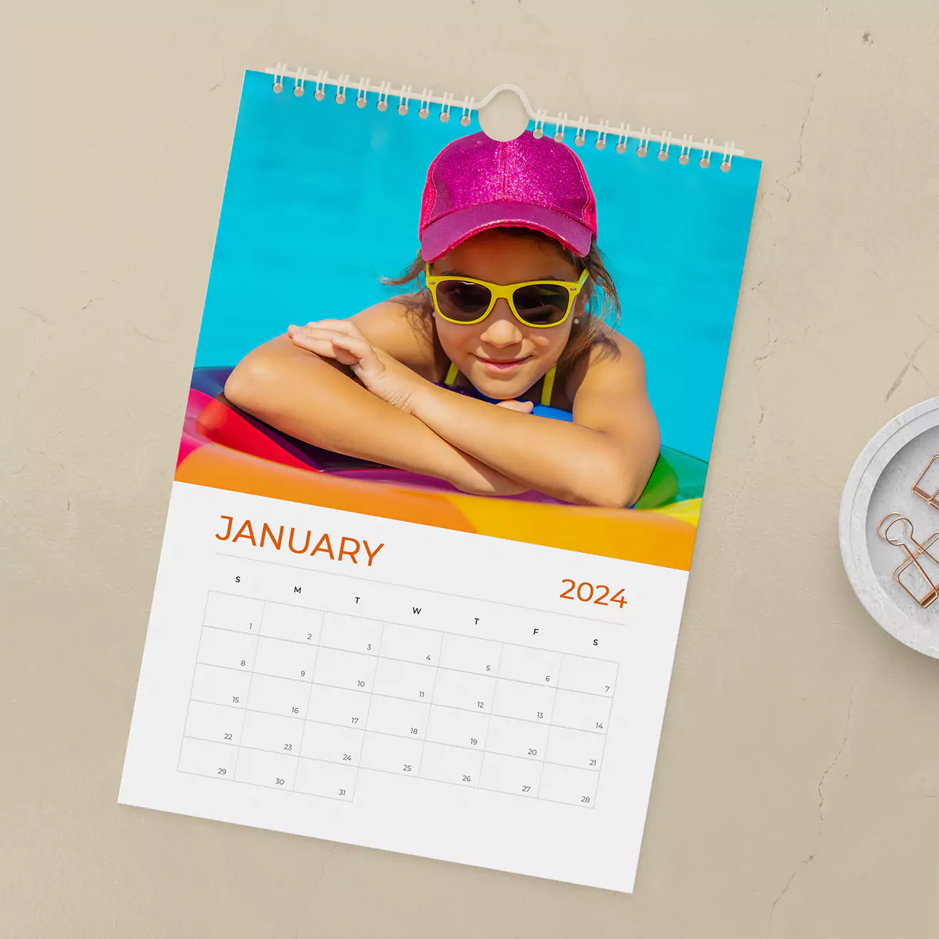 Personalised wall calendar for 2023 featuring a colourful cover photo of a child in sunglasses and a cap, leaning on a pool float. The calendar is open to January, displaying dates in a clean, modern layout. Ideal for gifts, including Christmas and baby shower gift ideas.