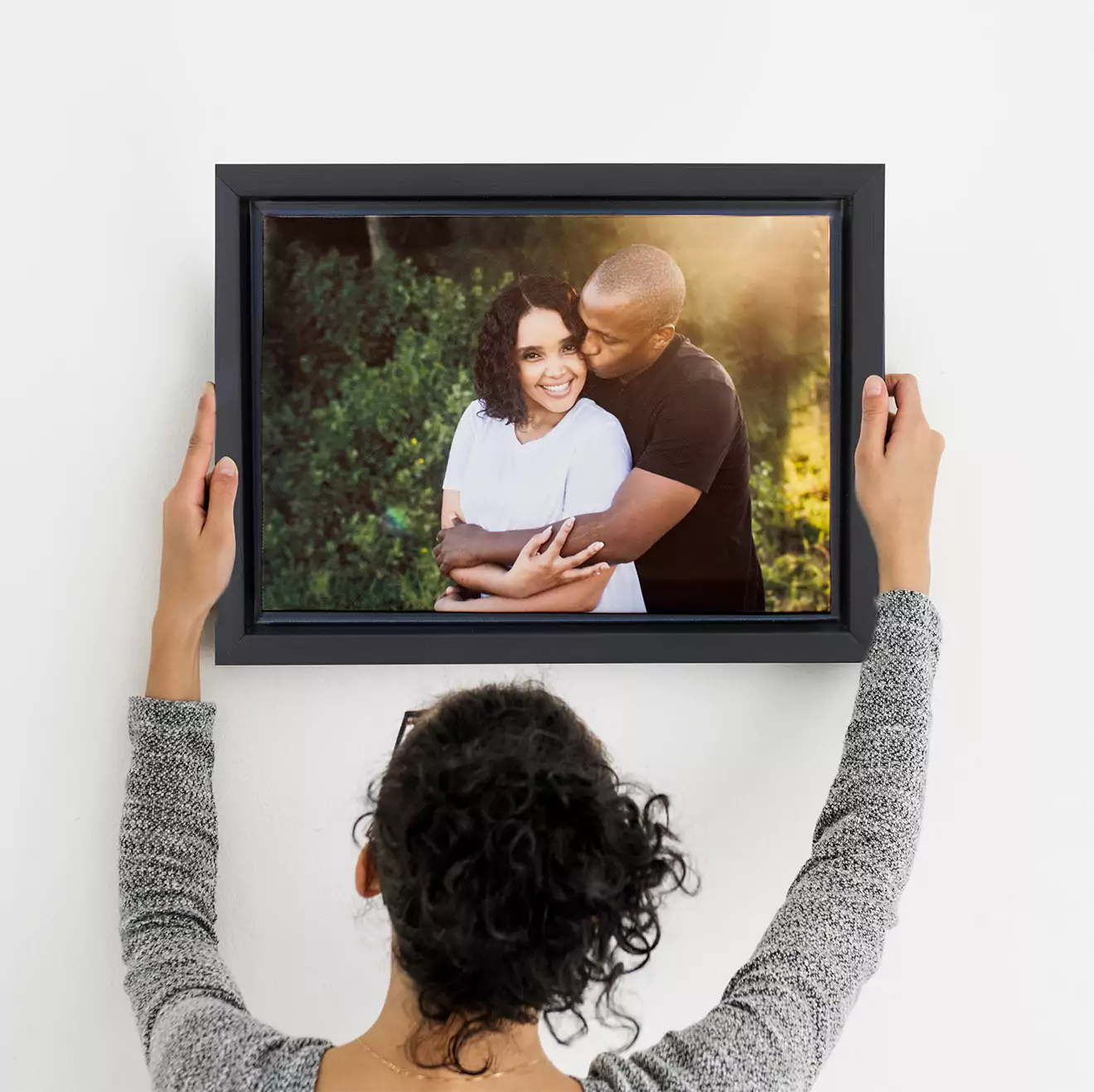 A large canvas print featuring a baby in a light blue outfit, lying on their stomach and looking forward. The canvas is propped against a wall in a cosy room with a wooden rocking horse and a soft beige blanket visible. Ideal for baby shower gift ideas or personalised gifts in South Africa.