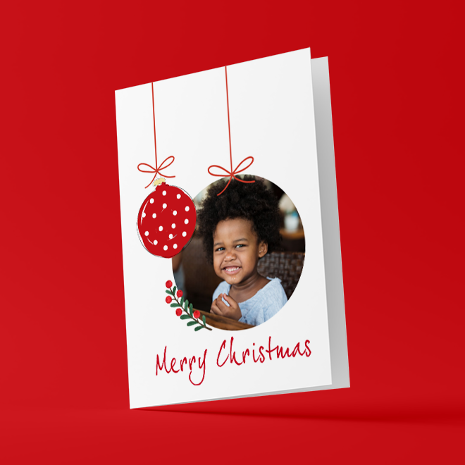 Personalised Christmas card featuring a photo of a child inside a circular frame, adorned with a red and white polka dot bauble illustration. The card has a ''Merry Christmas'' message in red script at the bottom, set against a white background with a red border. Ideal for Christmas gifts and personalised holiday greetings.