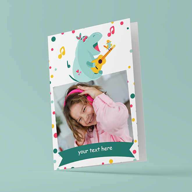 Customisable greeting card featuring a playful hippo illustration playing a guitar, surrounded by colourful musical notes and confetti. The card has a photo slot displaying a smiling child wearing headphones and a space for personalised text. Ideal for various occasions and personalised gifts in South Africa.