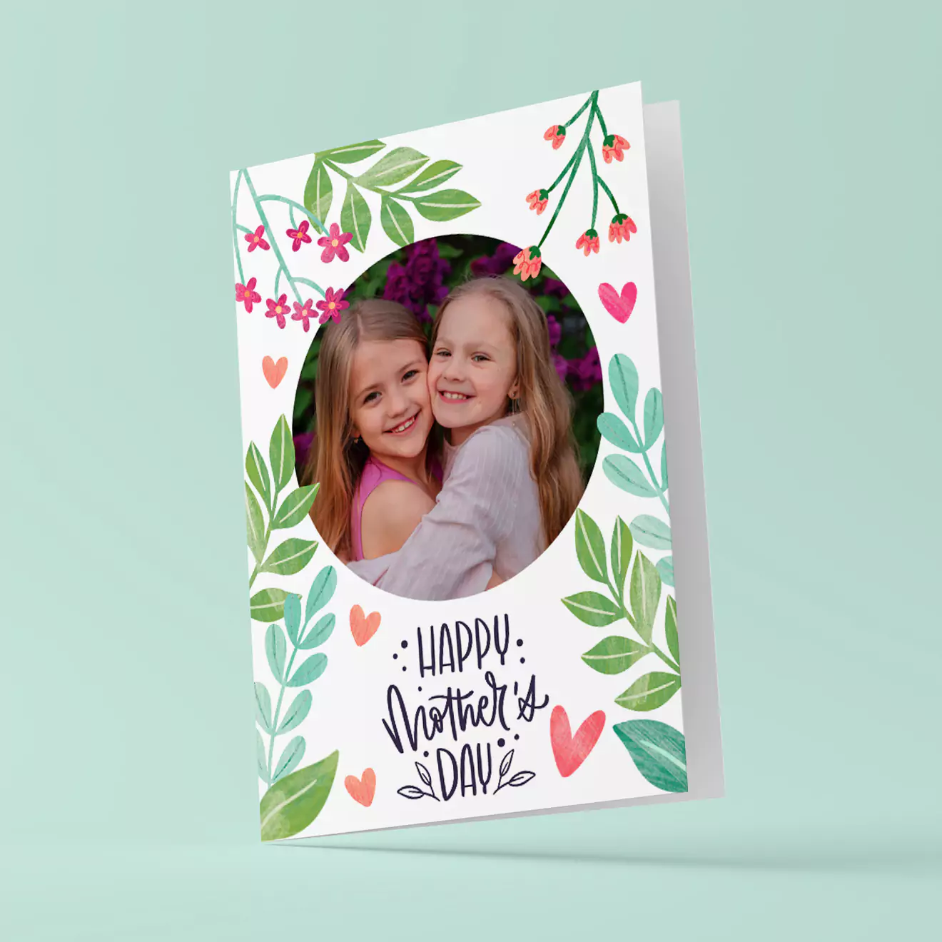 Mother''s Day greeting card featuring a floral design with green leaves and pink flowers. The card has a circular photo of two smiling girls in the centre and the text ''Happy Mother''s Day'' in a stylish font below the photo. Ideal for personalised gifts in South Africa.