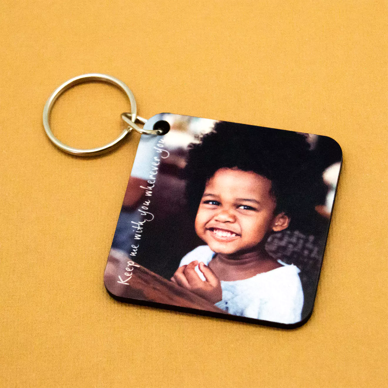 Square personalised keyring featuring a smiling child on a yellow background. The keyring has a metal ring and a printed photo, making it an ideal gift for various occasions such as birthdays, baby showers, or Christmas. Perfect for keeping cherished memories close.