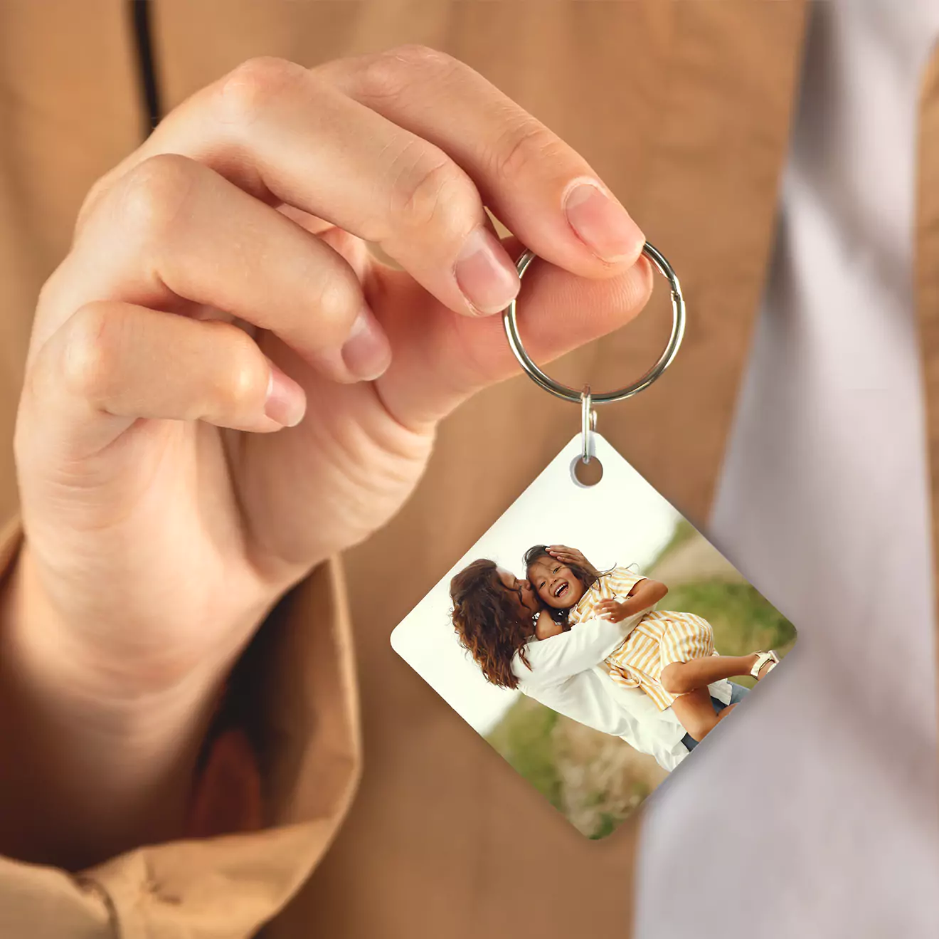 Close-up of a hand holding a personalised keyring featuring a square photo of a smiling woman and child. The keyring has a metal ring and a glossy finish, making it a perfect gift idea for various occasions such as Christmas, Valentine's Day, or birthdays. Ideal for personalised gifts in South Africa.