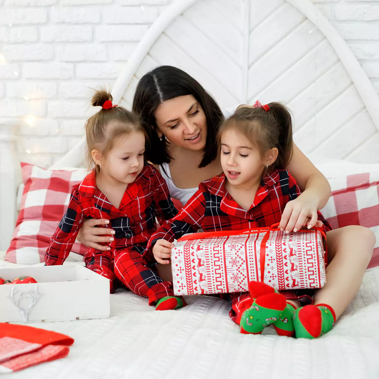 Image of a family opening presents while dressed in cozy Christmas pajamas, gathered around a festively decorated living room, capturing the warmth and excitement of holiday gift-giving.