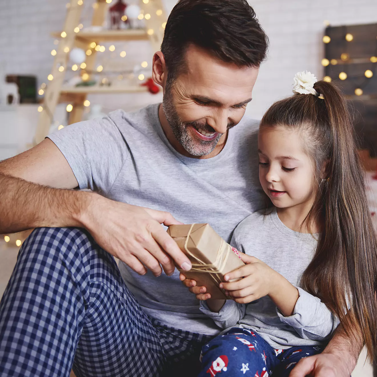 Image of a father giving his daughter a Christmas present, capturing a tender moment of joy and surprise during the holiday celebrations, emphasising the warmth of family gift-giving.