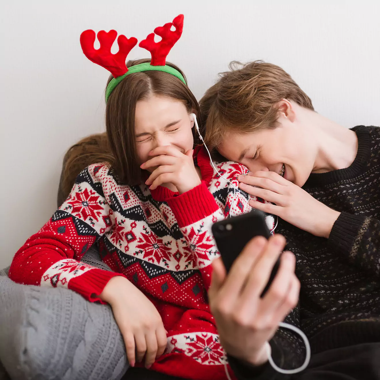 Image of teenagers sharing a laugh, wearing festive Christmas headwear, enjoying a joyful, spirited holiday gathering, emphasising the fun and camaraderie of the season.