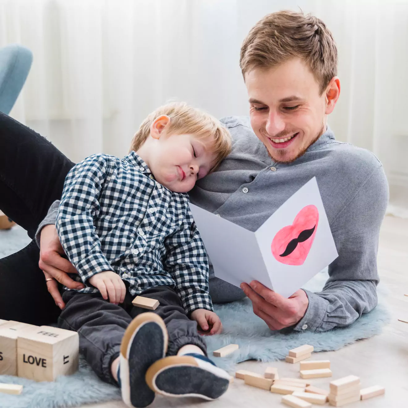 A young dad with a child sleeping on his chest, looking at a personalised card made for him. A heartwarming gift for Father's Day or any special occasion, celebrating fatherhood. Thoughtful gift ideas in South Africa.