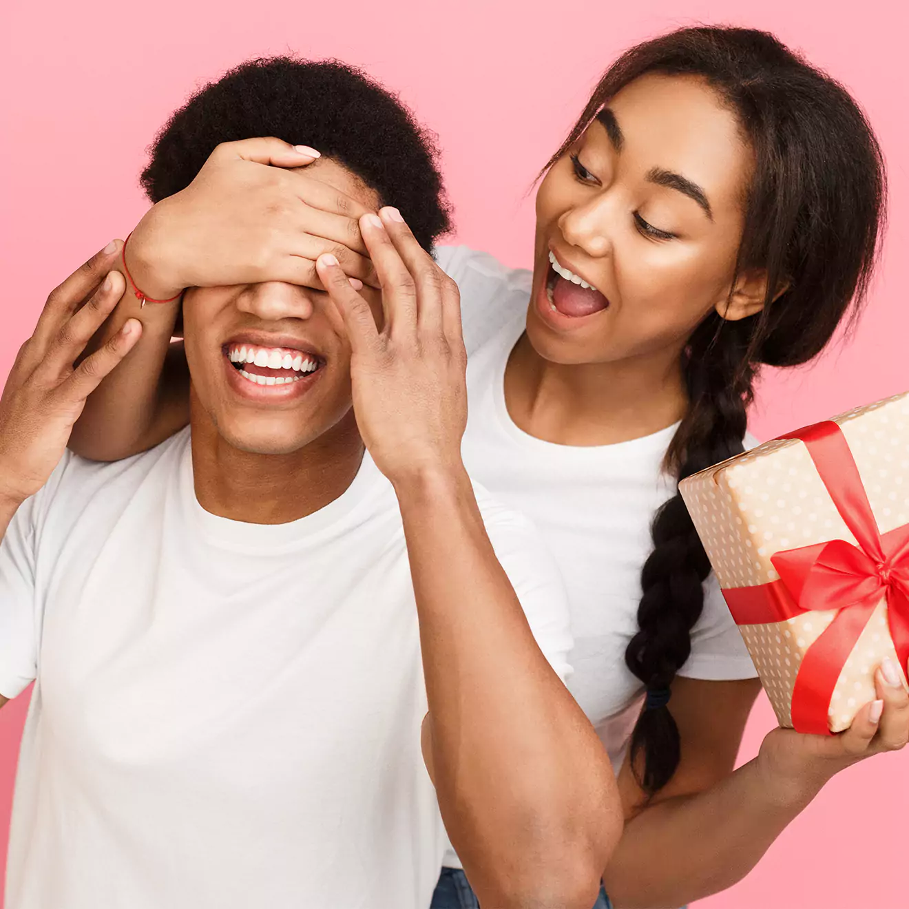 Image of a girl playfully blocking a man's eyes while surprising him with a gift, capturing a romantic and fun Valentine's Day moment, perfect for inspiring gift ideas.