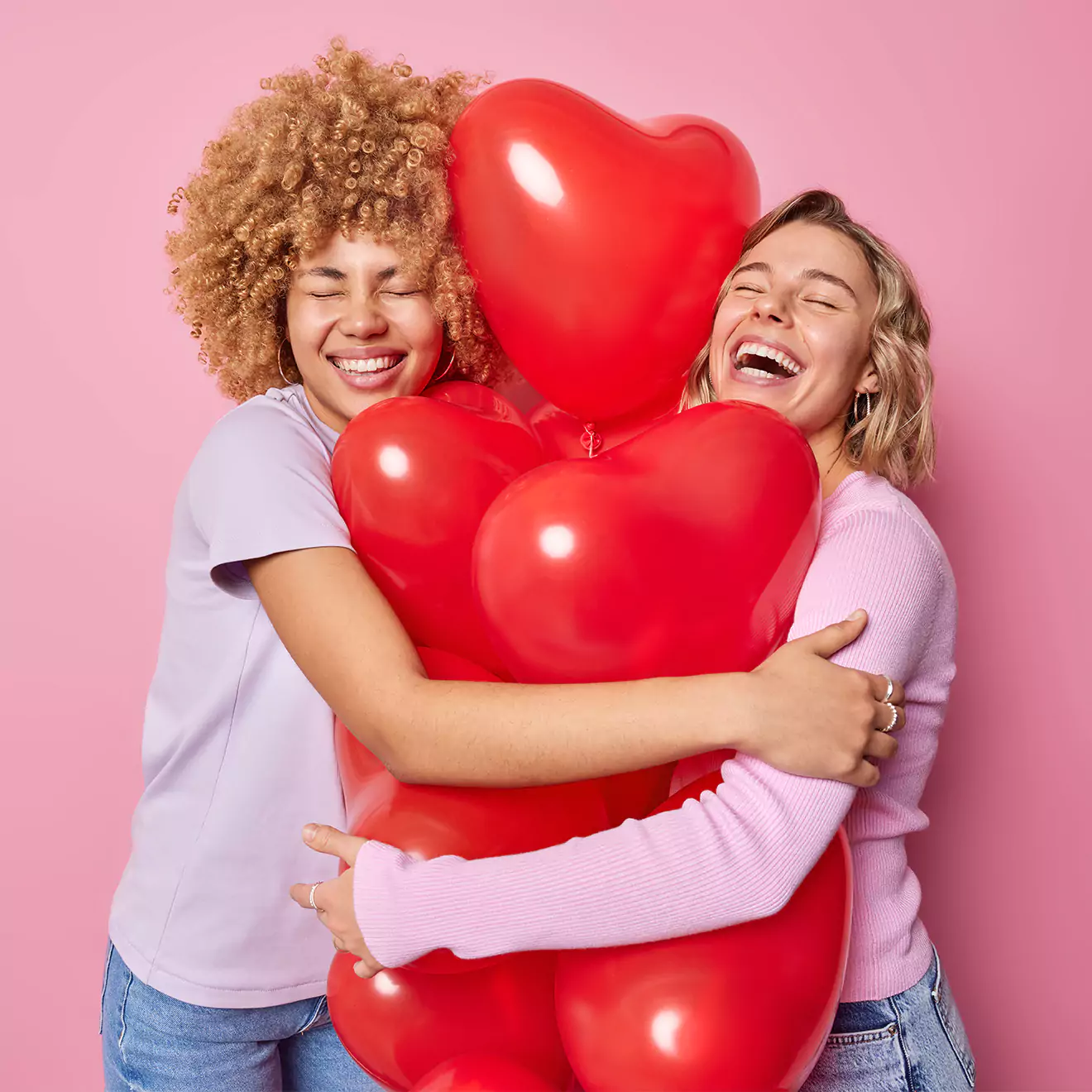 Image of a couple smiling and hugging, with a bunch of heart-shaped balloons between them, capturing a joyful and romantic Valentine's Day celebration, perfect for expressing love and affection.