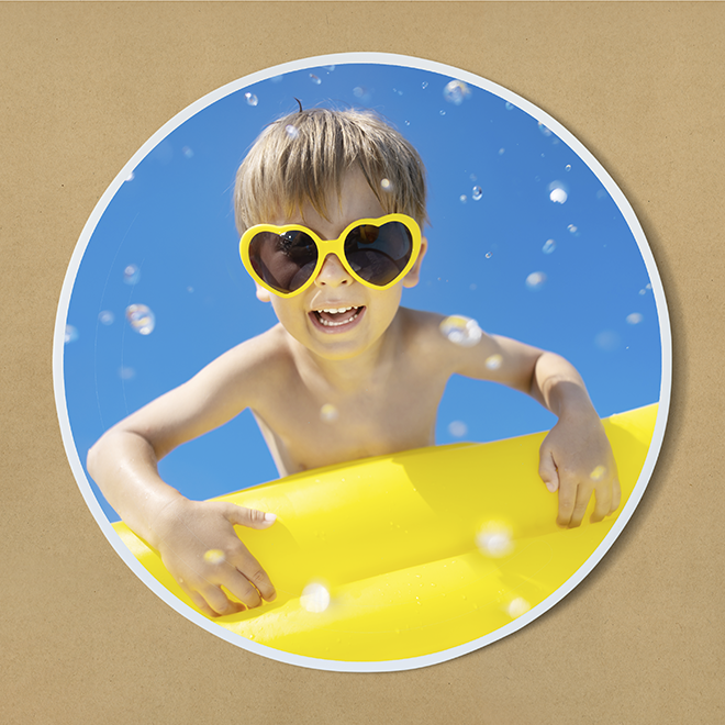 Round photo print featuring a young child wearing heart-shaped yellow sunglasses, smiling and leaning on a yellow inflatable against a bright blue sky background. Ideal for personalised gifts, photo albums, or photo books. Perfect for capturing joyful summer memories.