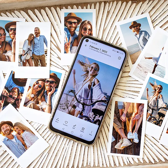 A collection of printed photos featuring a couple enjoying various outdoor activities, arranged around a smartphone displaying a photo of the same couple. The photos are laid out on a textured surface, showcasing vibrant and joyful moments. Ideal for personalised gifts, photo albums, or creating a photo book.