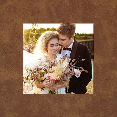 A photobook or album cover featuring a romantic couple embracing outdoors, with the woman holding a bouquet of flowers. The cover has a brown leather-like texture.