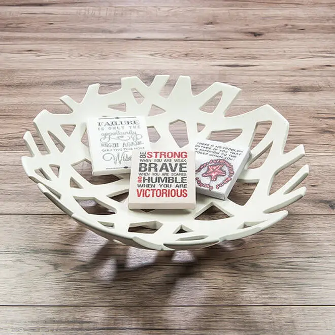 Decorative white ceramic bowl with an intricate, openwork design, placed on a wooden surface. Inside the bowl are three small, rectangular items featuring motivational quotes and designs. Ideal for home decor, gifts for men, or Christmas gift ideas.