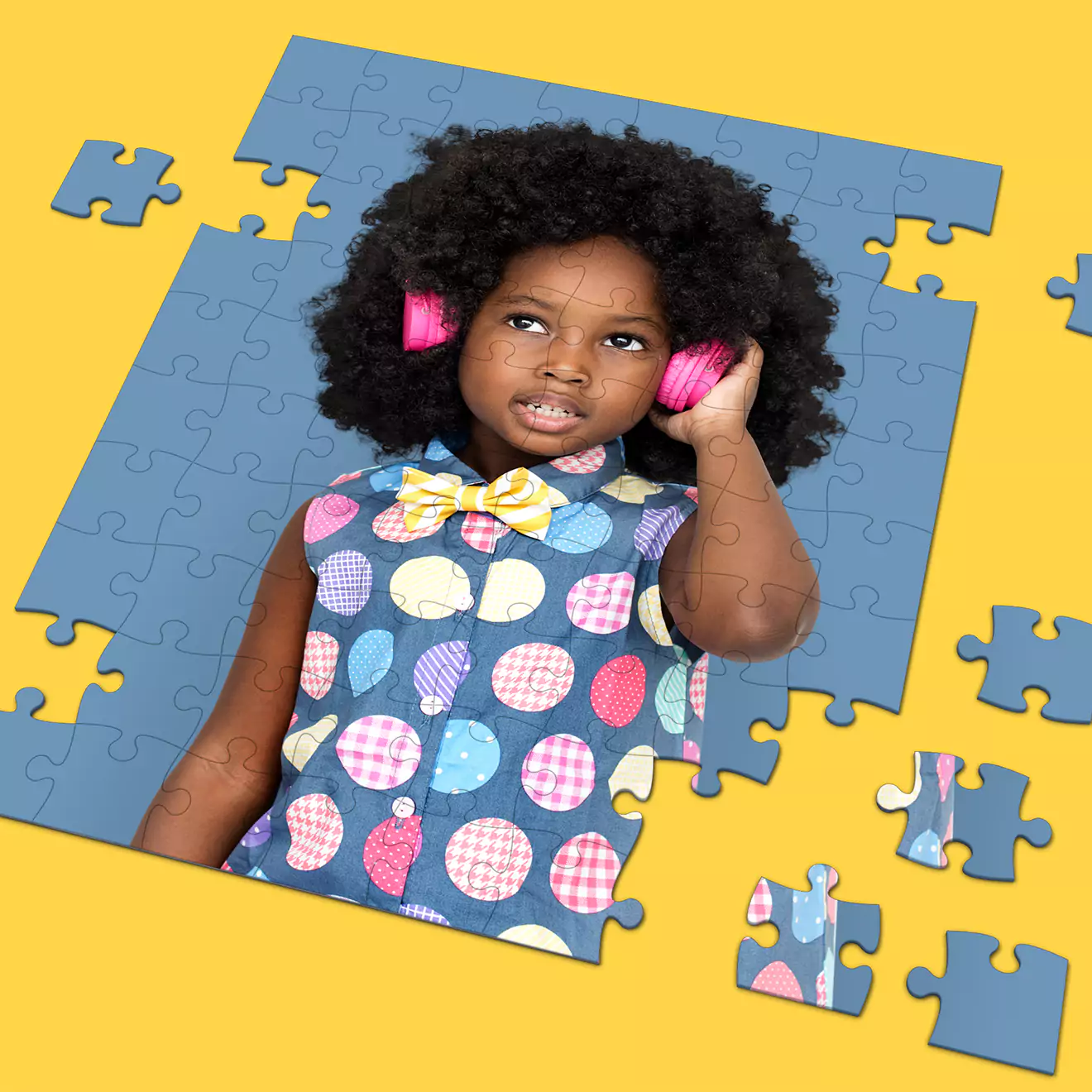 Customisable jigsaw puzzle featuring a young girl with curly hair wearing pink headphones and a colourful polka dot dress. The puzzle pieces are scattered on a yellow background, showcasing a partially completed image. Ideal for personalised gifts in South Africa.